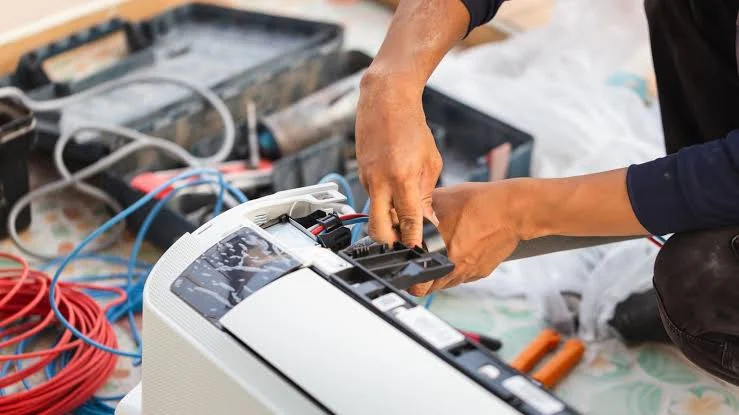 Hands repairing wiring inside an indoor air-conditioning unit