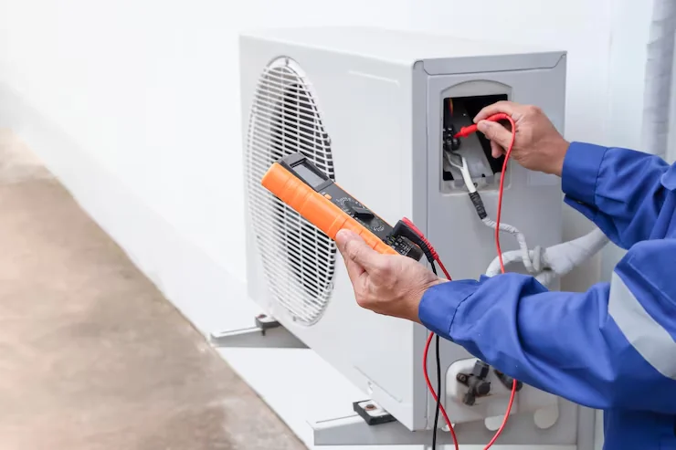 Technician using a multimeter to test an outdoor air-conditioning unit