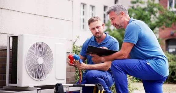 Two HVAC technicians reviewing a condenser inspection with a clipboard
